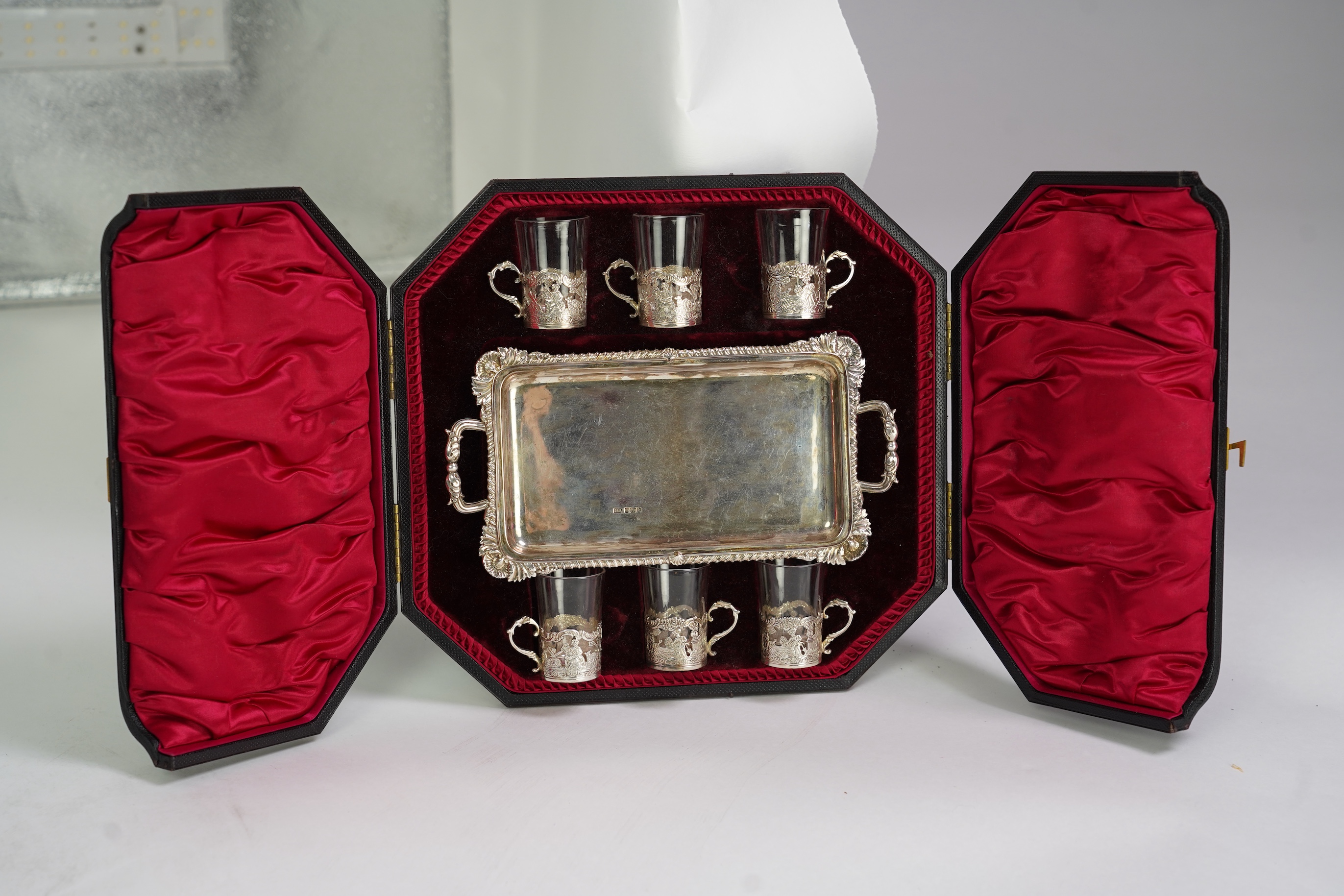 An Edwardian cased silver small two handled serving tray with six matching silver mounted glass liqueur tots, by Atkin Brothers